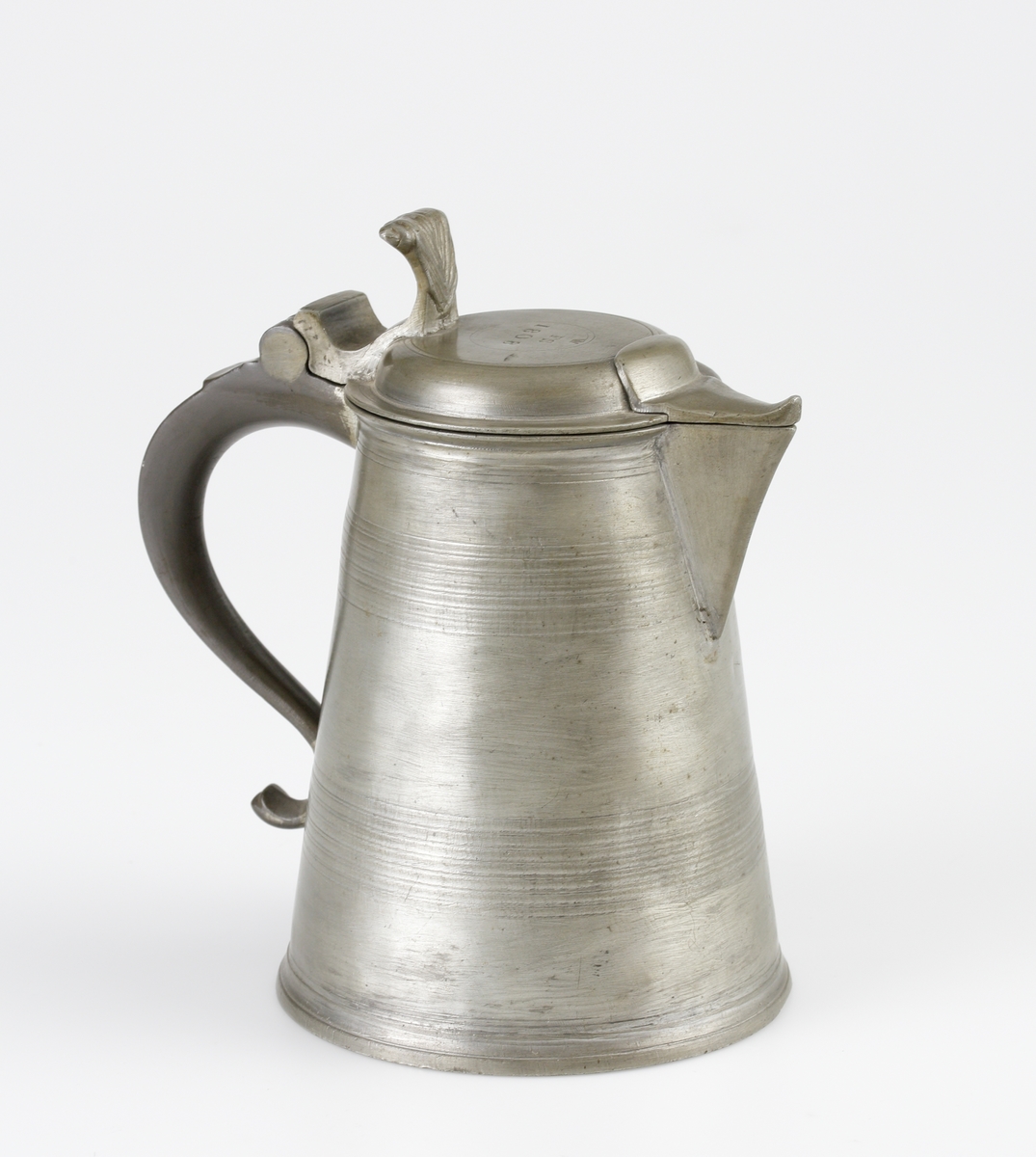 Stop av tenn.
Konisk, bandad modell. Svängd hänkel och ornerat, svängt tumgrepp. Svängd snås. 
Ovanpå locket är stämplat en krona, ägarinitialer: "FS" och årtalet 1808. 

Inskrivet i huvudbok 1982.