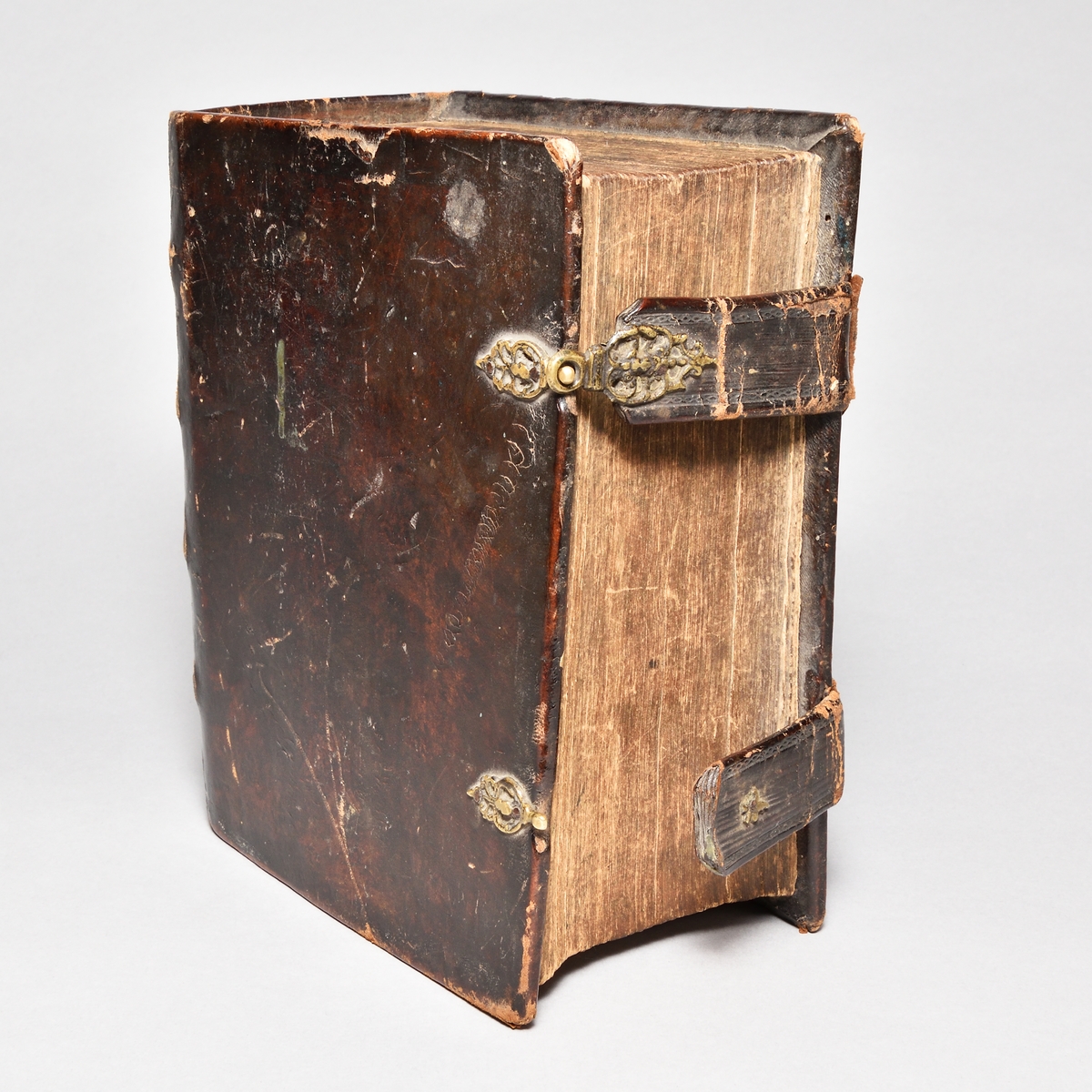 Bibel med band av skinn, rygg med fyra upphöjda bind. Två bokspännen av skinn och mässingsknäppen.