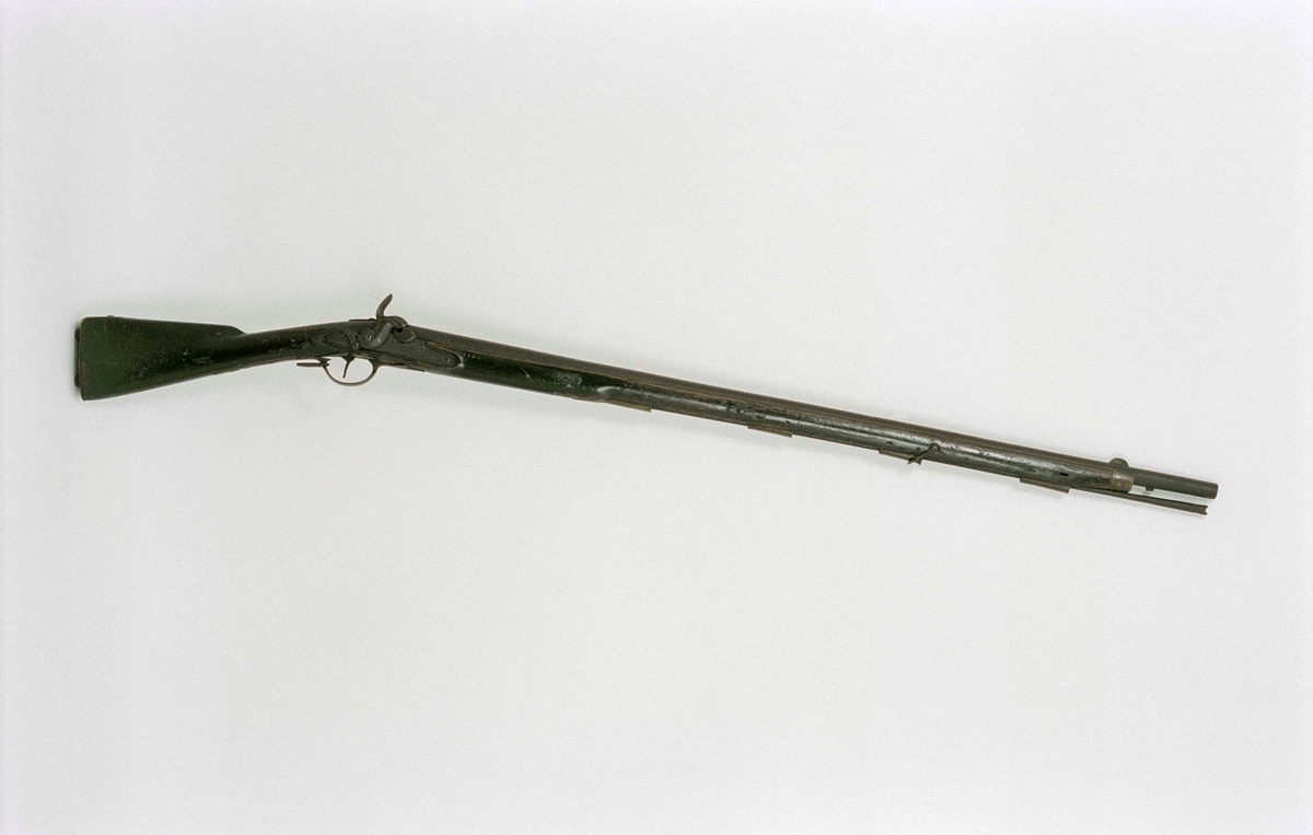 Mynningsladdad bössa med slaglås. Kolv och stock av svartmålat trä, beslag och laddstakshylsor (4 st) av mässing, laddstake av järn, avlångt korn av mässing. Slätborrad pipa. Tjockt låsbleck med varhake (och "stopptapp"). Rutat tumgrepp på hanen. På låsbleck, pipfäste och snäcka stämplat "K"; på stock, låsbleck och pipa "1184"; på sidbeslaget stämplat "I C 41".
Knallhattstappen av.