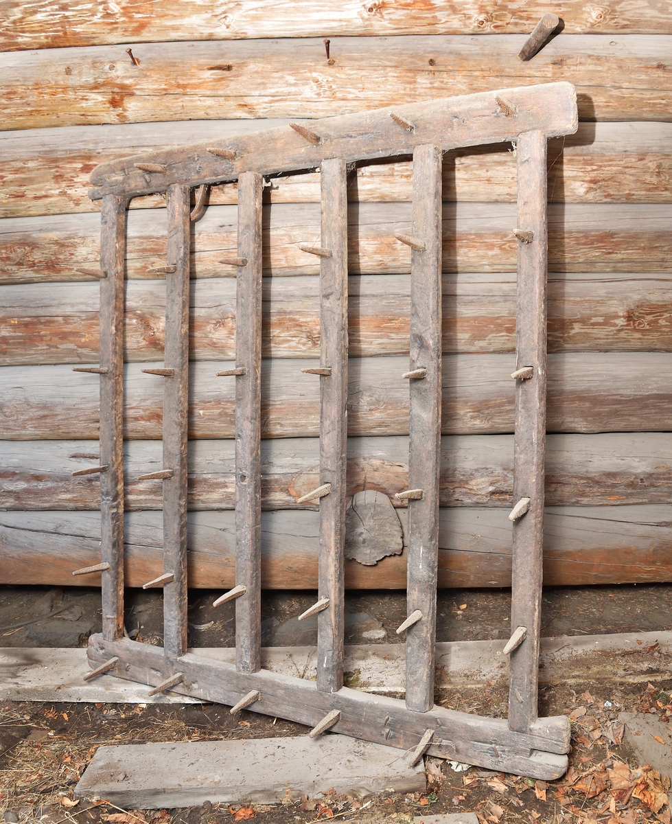 Pinnharv med kvadratisk ram av trä med 6 st tvärslåar försedda med järnpinnar. På ovansidan två halvcirkelformade fästen av järn.