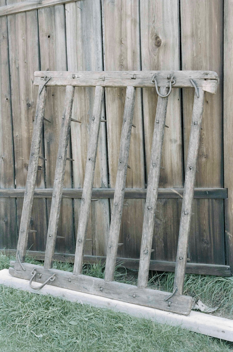 Pinnharv med kvadratisk ram av trä med 6 st tvärslåar försedda med järnpinnar. På ovansidan två halvcirkelformade fästen av järn.