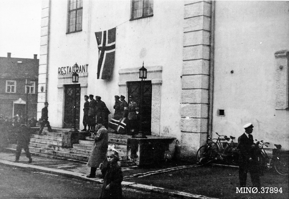 Bygning med norsk flagg og mennesker utenfor