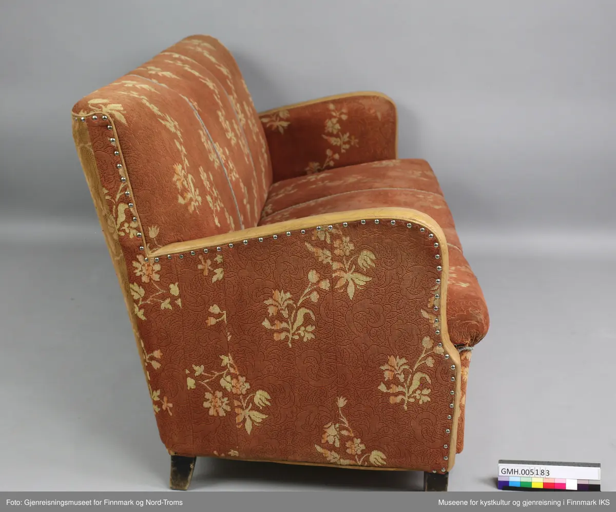 Sofaen er en treseter der rygg og setet er avgrenset med tvinnede pyntebånd i grått. Rygg, sete og armlener er polstret og trekt med et stoff som har rødbrun bunnfarge og et lysebrunt blomstermønster. Trekket er spikret til ramma på undersiden og på armlenen på utsiden. På kanten er armlenene trekt med lysebrun kunstskinn. På undersiden er sofaen lukket med plater, slik at polstringa ikke er tilgjengelig. Det er likevel synlig at sofaen består av en ramme med to tverrforbindelser. Dette er et inngrep som mest sannsynlig er gjort for å få støttet opp under sylinderfjærene. 