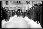 Hålahults sanatorium, exteriör, tvåhjulig öppen vagn, häst och vagn framför porten, snö på marken, två granar vid port, flaggor, mycket folk på båda sidor av gången