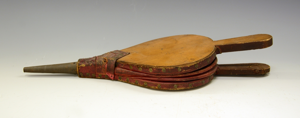 Ovnsbelg. Fra protokoll: Omnsbelg (omspustar)  i uvand blekkpipe. pæreforma bokvedbynir, raudt saffiand skinn, nagla med salmakarstiftur. Lengd med skaft og pipe 38,5 cm.