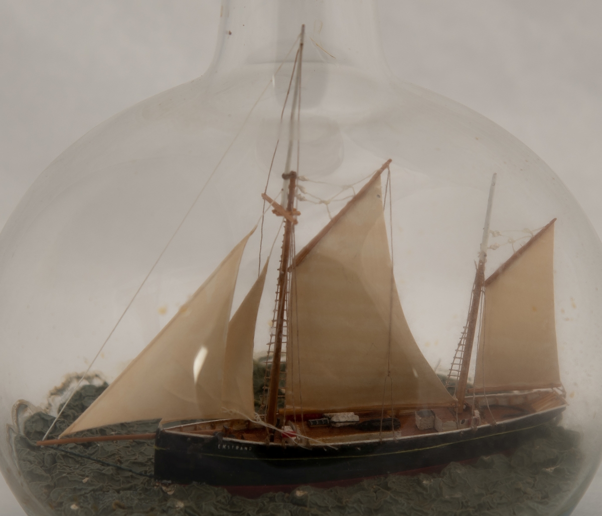 Flaskeskute: "Ekstrand" , galeasrigget kutter , før ombyggingen i 1990.  Kuleformet flaske av klart glass . Sortmalt skrog , rød under vannlinjen , hvit kant , hvite seil. Lys blågrønn kruset sjø.