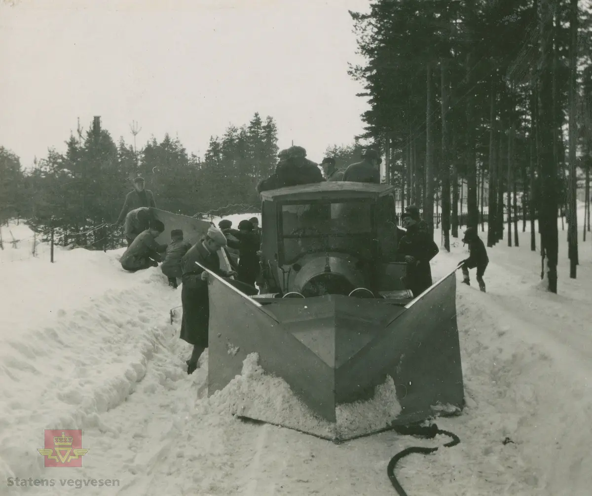 Bilde 1 og 2) Tekst som medfølger bildet: "Fotografier innkommet med Øveraasens skrivelse av 9/12-1927. Forplog med rømmevinger levert Gausdal Bilselskap. Plogen er 2,3 meter bred. 65 cm Foran, 1 meter bak hvor rømmevinger påsettes". 
Øveraasens forplog med rømmevinger påmontert Opel lastebil.  Opel var uvanlig som lastebil i Norge så tidlig, dette er en bil produsert før 1925.  Opplysninger til kjøretøyet gitt av Asbjørn Rolseth. 
Bilde 3) Bilde med tekst av Øveraasen skrivelse 9-12-1927.
Bilde 4) Dette er bilde fra album "Snebrøyting" 1918-1934 som er merket: "Øveraasens nye forplog og sideplog. Elverum 14.03.1928. Bemerk: Rømmmeving på forplogen." Mange menn er med på prøveforsøk av den nye plogen. 
Bilde 5) Bilde med tekst fra Øveraasens nye forplog og sideplog. Elverum 14-3-1928. 
Se NVM 00-F-33454 Relasjon og relaterte objekter  lenger ned på siden. Her står også opplysninger om lastebilen. 

Ref. til "Meddelelser fra Veidirektøren", Nr. 10- og Nr. 11-1931: "Snerydningen på våre veier vinteren 1930-1931". 
Ref. til "Meddelelser fra Veidirektøren", Nr. 3-1930,  "Snebrøytingsforsøk med 6-hjulere," av overingeniør N. Saxegaard.