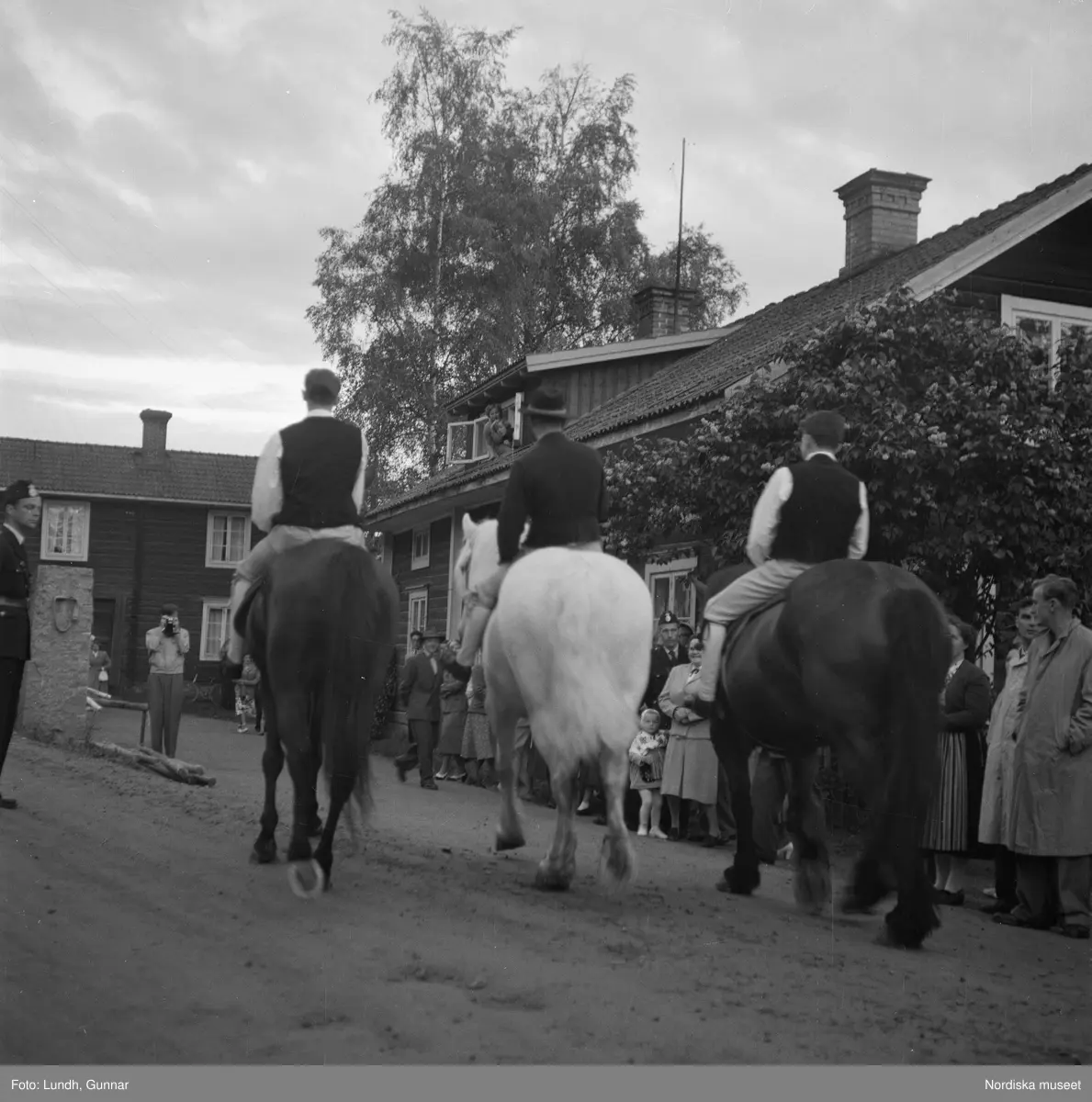Motiv: (ingen anteckning) ;
En kvinna och två män spelar boccia, porträtt av en kvinna i folkdräkt, en folksamling står vid en gärsgård, tre män i folkdräkt rider på hästar framför män som spelar fiol och kvinnor i folkdräkt som går på en väg "Midsommartåget till Tibble", en kvinna i folkdräkt rider på en häst som drar en vagn med barn, kvinnor och män pryder en midsommarstång med lövade ringar.dju
