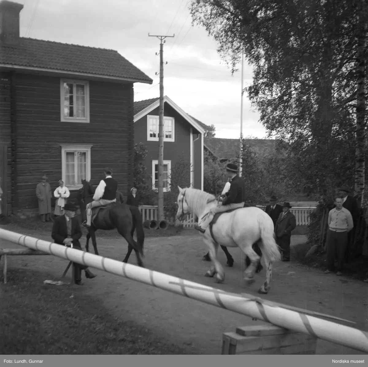 Motiv: (ingen anteckning) ;
En kvinna och två män spelar boccia, porträtt av en kvinna i folkdräkt, en folksamling står vid en gärsgård, tre män i folkdräkt rider på hästar framför män som spelar fiol och kvinnor i folkdräkt som går på en väg "Midsommartåget till Tibble", en kvinna i folkdräkt rider på en häst som drar en vagn med barn, kvinnor och män pryder en midsommarstång med lövade ringar.dju