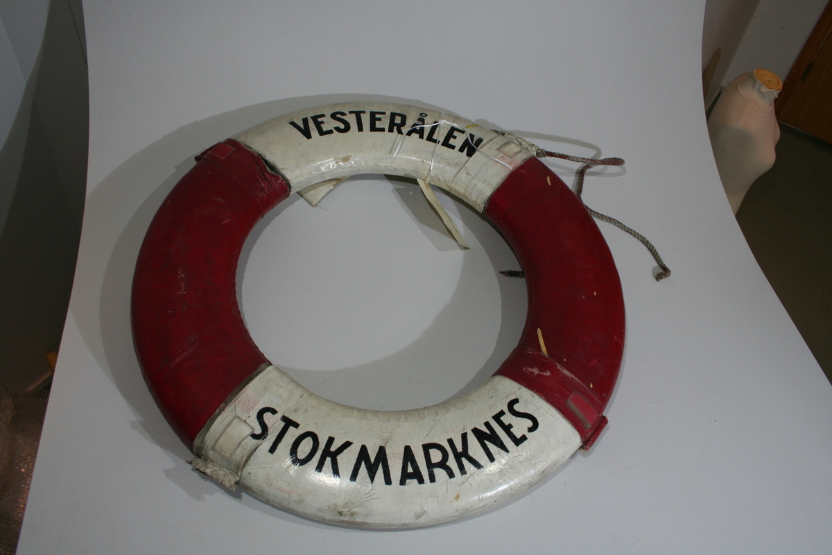 Ringformet livredningsbøye i kork overtrukket med et vannavstøtende materiale, trolig lerretstoff, seilduk. Hvite og røde felter. Tauet som skal henge på yttersiden henger bare fast i en av de fire hempene og er fort kort til å henge rundt.  Ytterstoffet har enkelte steder revnet i sømmene, og refleksen har delvis blitt borte. Redningsbøyen har noen lysegule malingsflekker. På baksiden har det blitt en stor revne i det ene hvite feltet.