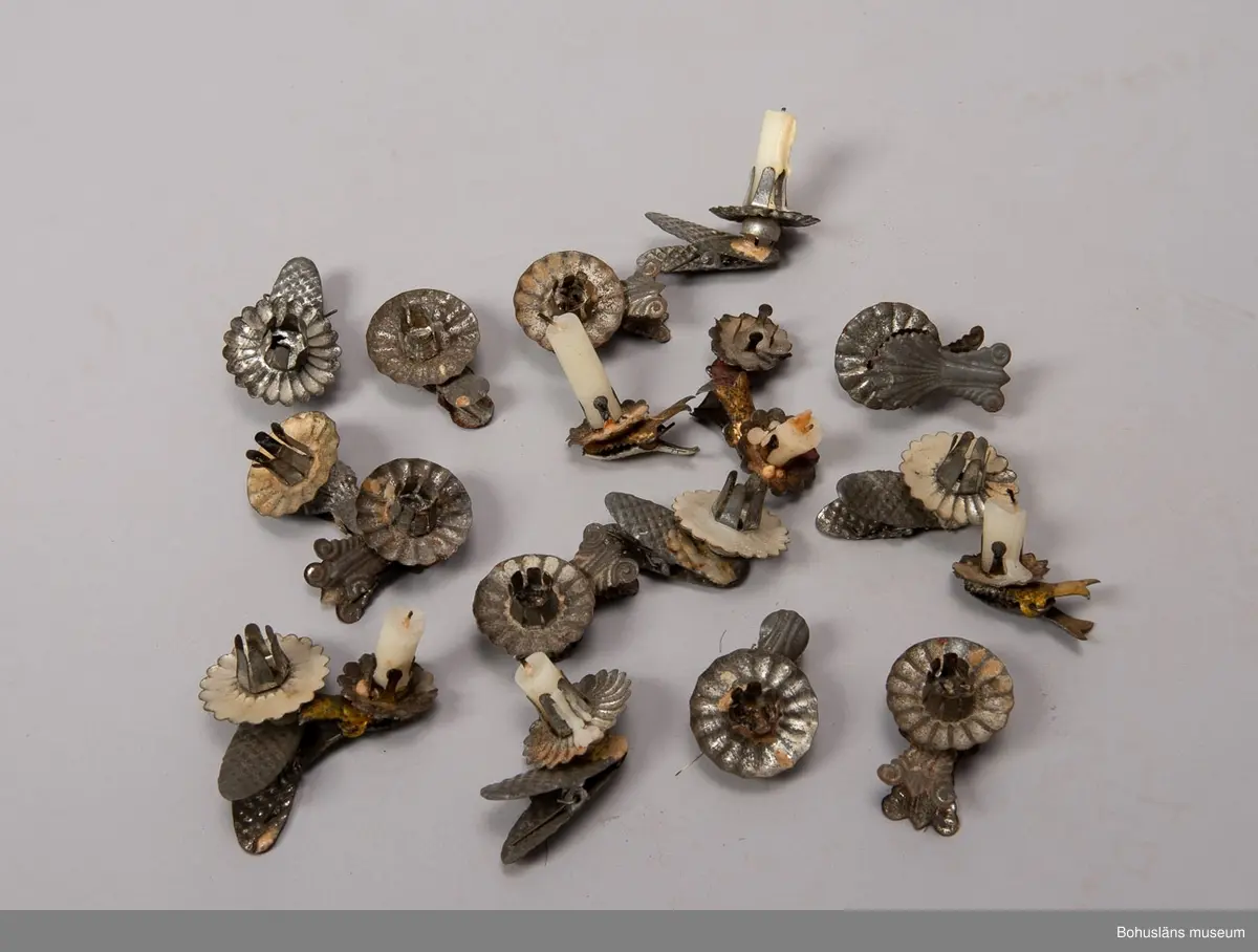 Låda av brun papp. På locket påklistrad,delvis bortsliten etikett med text: "Herman Radyn Uddevalla". Lådan innehåller: 19 st. julgransljushållare, glitter i silver, glitterband i guld, 7 st. julgranskarameller av papper, 1 toppstjärna, 12 st. hjärtan av papper i olika färger, 6 st. små glasbollar i sytråd, svenska flaggor i tråd, 12 st. svenska flaggor med järntråd,