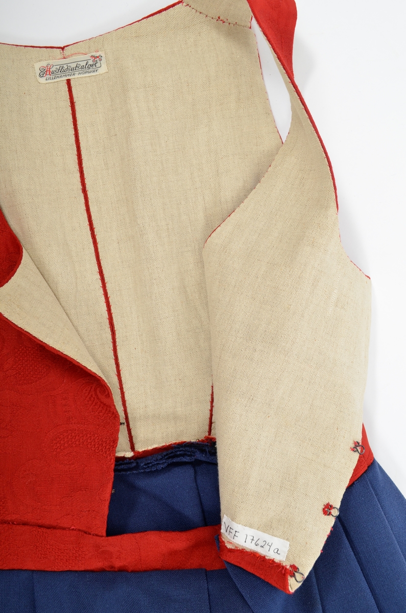 Grafferbunad med raudt damaskvove ulltøy i livet, og blått toskaftvove ulltøy i stakken. A. Livet har opning framme festa saman med tre hekter og krokar. Saum midt bak, og med to svinga ryggsaumar. Fóra med ubleikt halvlin.
Stakk i toskaft-vove ulltøy, brodert med ullgarn i forskjellige fargar. Rosemotiv. Den er foldelagt. Brei skonnering av svart bomulltøy i  nedrekanten.
B. Jakke i blått toskaftvove ulltøy. Opning midt framme med tre hekter og krokar til lukking. Eit snitt på kvar side. Erme er foldelagt oppå skuldera og nede ved ermekragen. 
C. Lue, pullue, i same tøy og broderi som stakken. Fóra med ubleikt halvlin. I nedrekant av pullen løpegang med rynka strikk. 
D. Lomme i same tøy og broderi som stakken. Sølvforgylt lommelås.