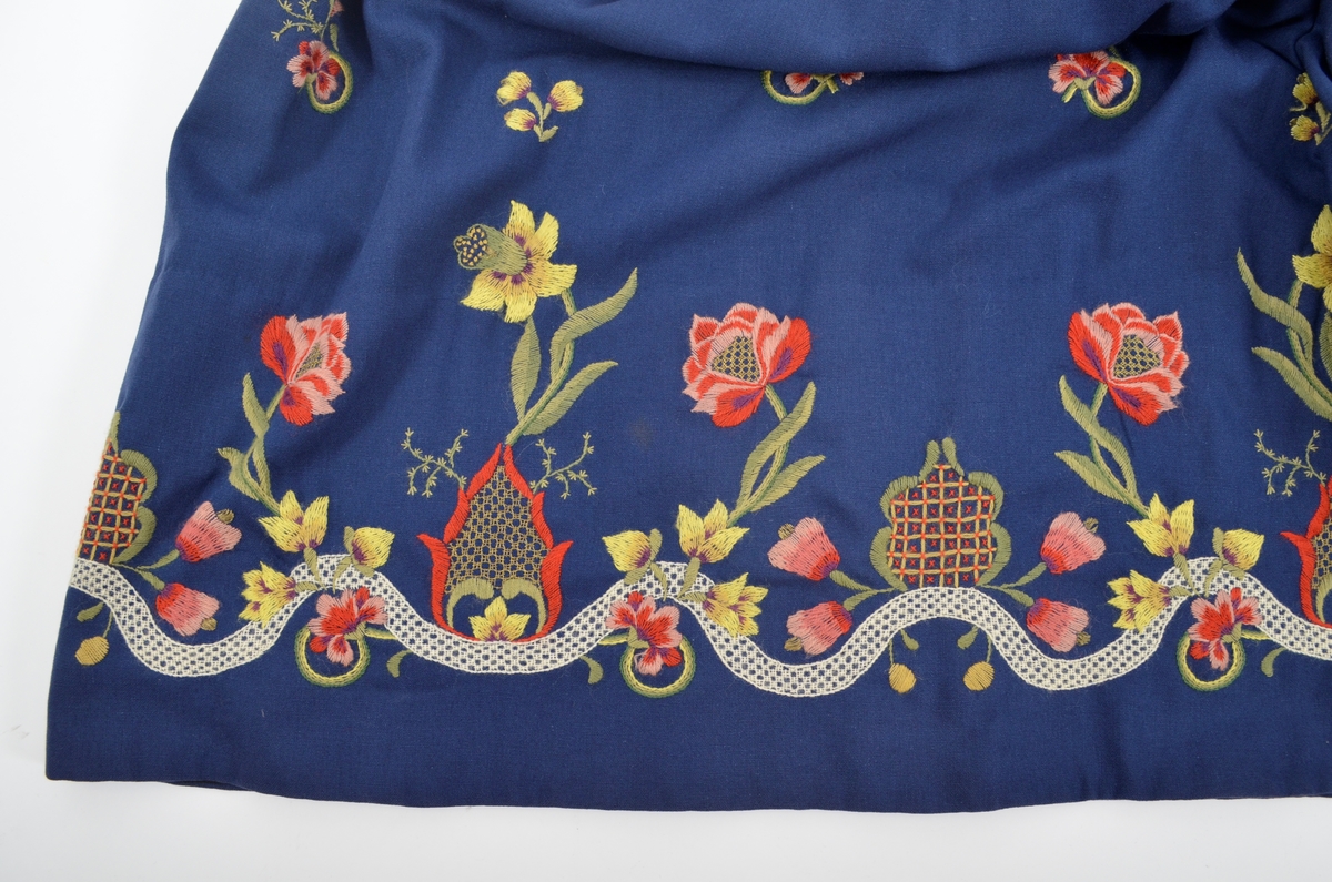 Grafferbunad med raudt damaskvove ulltøy i livet, og blått toskaftvove ulltøy i stakken. A. Livet har opning framme festa saman med tre hekter og krokar. Saum midt bak, og med to svinga ryggsaumar. Fóra med ubleikt halvlin.
Stakk i toskaft-vove ulltøy, brodert med ullgarn i forskjellige fargar. Rosemotiv. Den er foldelagt. Brei skonnering av svart bomulltøy i  nedrekanten.
B. Jakke i blått toskaftvove ulltøy. Opning midt framme med tre hekter og krokar til lukking. Eit snitt på kvar side. Erme er foldelagt oppå skuldera og nede ved ermekragen. 
C. Lue, pullue, i same tøy og broderi som stakken. Fóra med ubleikt halvlin. I nedrekant av pullen løpegang med rynka strikk. 
D. Lomme i same tøy og broderi som stakken. Sølvforgylt lommelås.