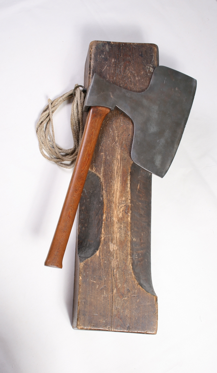 Skåret rektangulær treblokk med et smalt søkk til haken og et bredere søkk for halsen. Huggemerker og slitasje mellom de to søkkene.