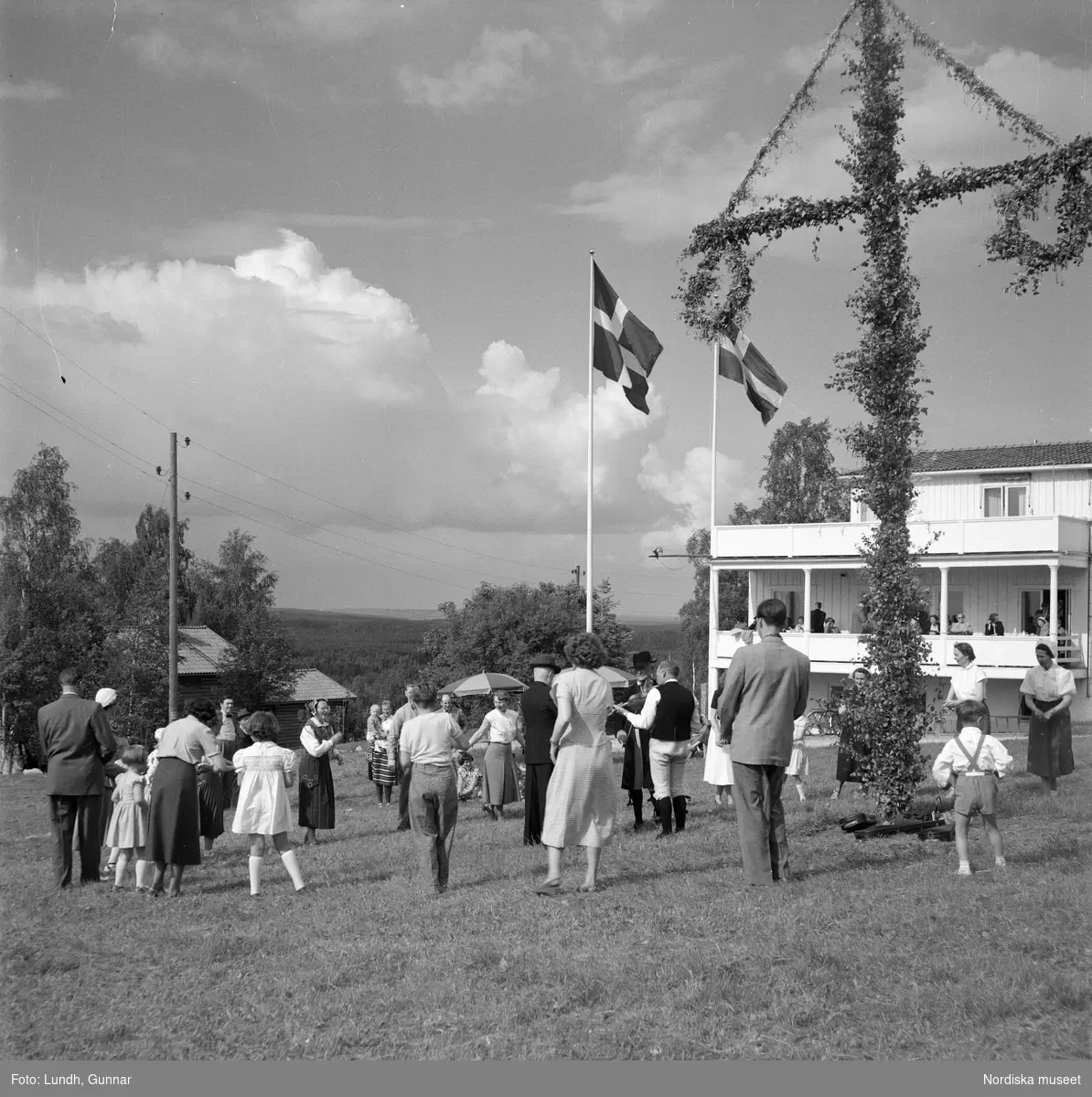 Motiv: Lerdalshöjden ;
Porträtt av en flicka som håller blommor, vuxna och barn dansar runt en midsommarstång, tre män i folkdräkt spelar fiol vid en midsommarstång.