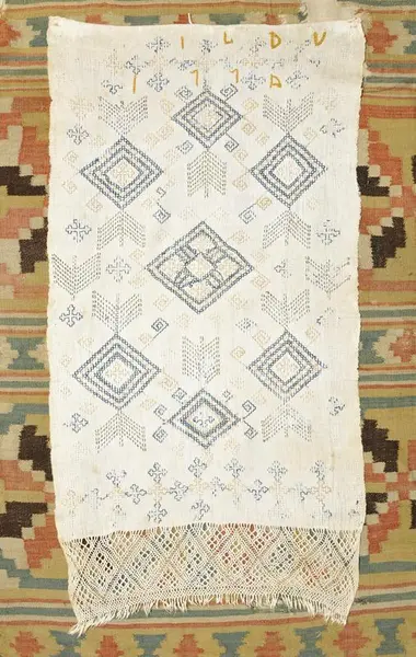 Kvitt julehandlle med firfletting, som heng over eit vevd åkle