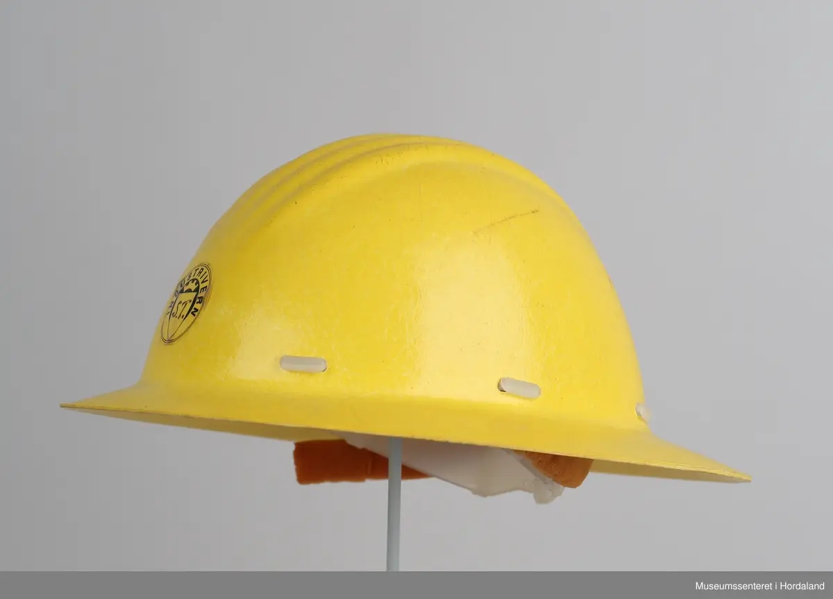 Hjelm i hardplast. Merka med "Industrivern S. T". Feste og reimer i plast på innsida.