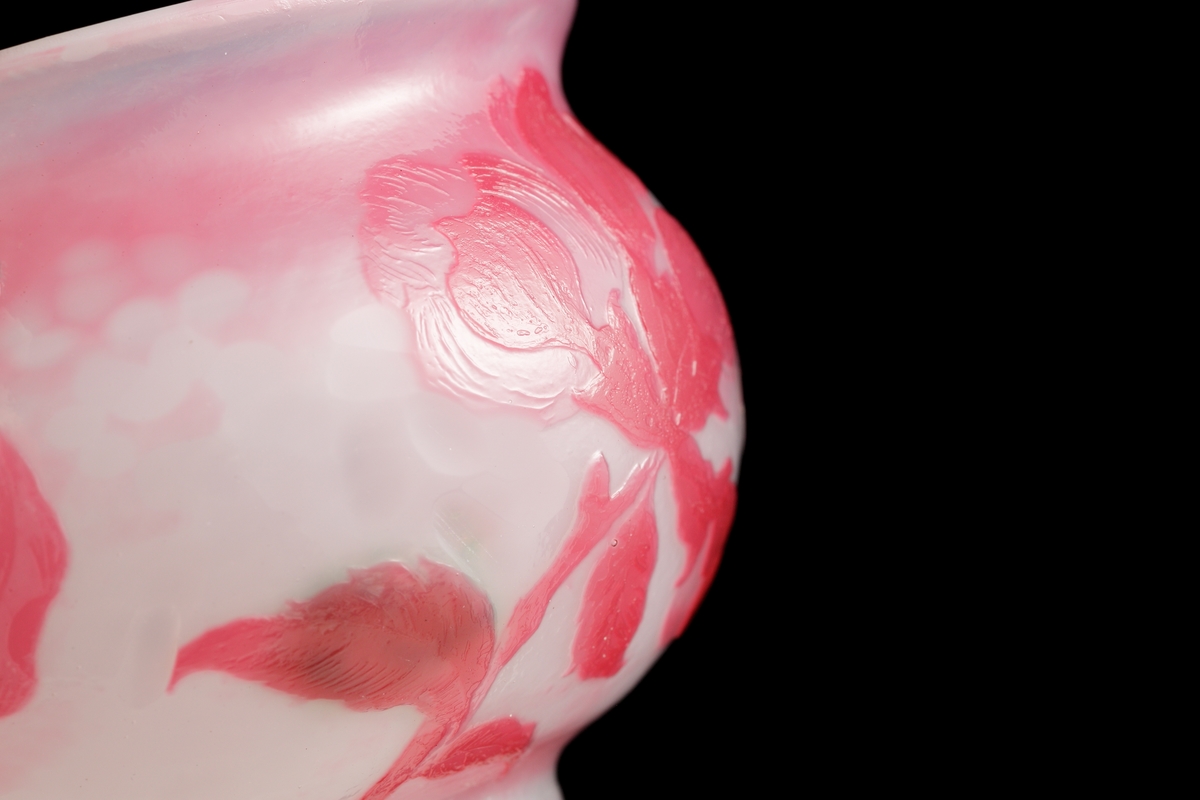 Skål med opaliserande vitt glas och mörkrosa överfång. Dekor av svagt stiliserad kvist med äppelblom. Gröna fläckar på insidan bakom bladen.