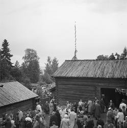 Motiv: (ingen anteckning) ;
En folksamling står kring en midsommarstång, en folksamling vid ett hus, en kyrkbåt ros av kvinnor och män i folkdräkt, en folksamling står vid en brygga med en kyrkbåt.