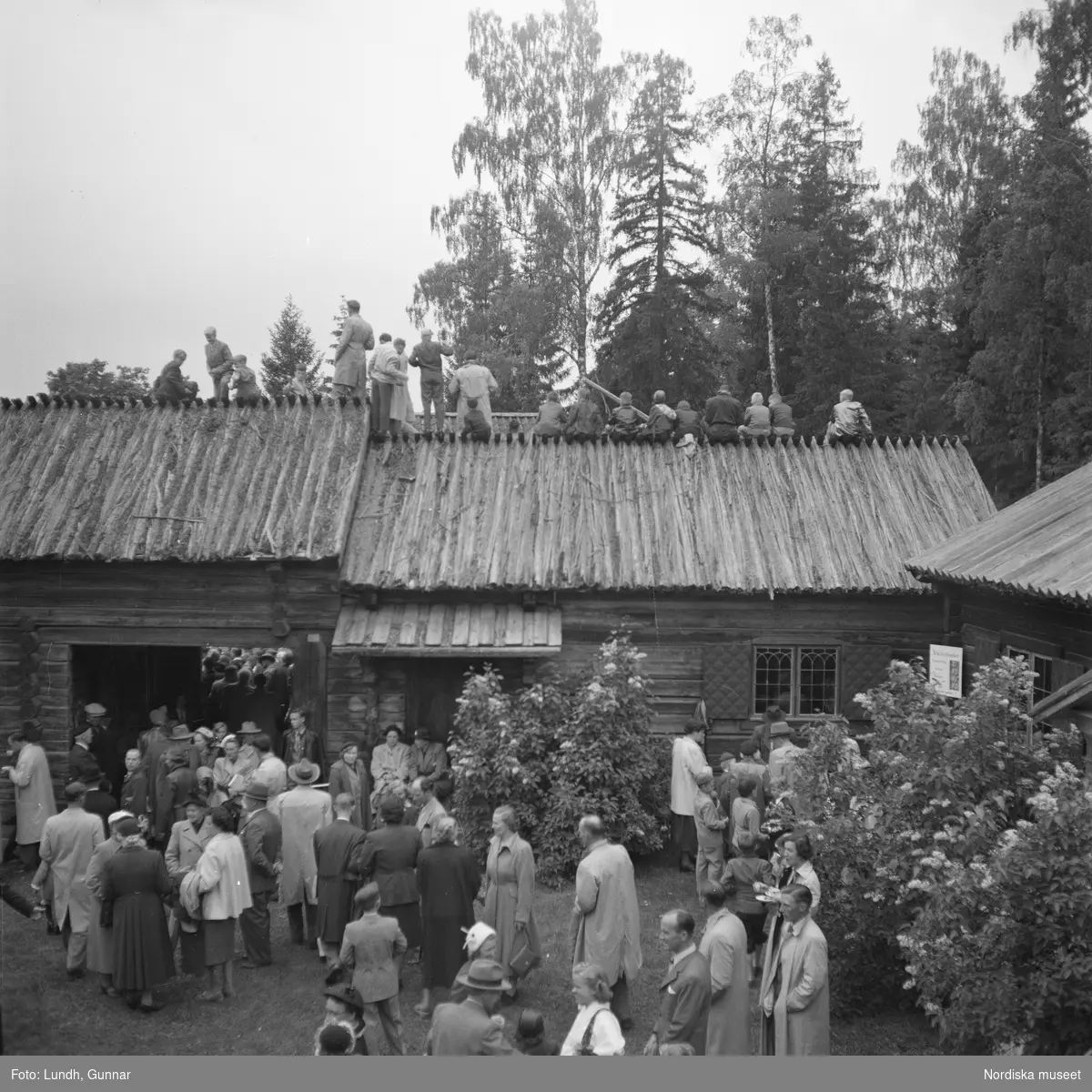 Motiv: (ingen anteckning) ;
En folksamling står kring en midsommarstång, en folksamling vid ett hus, en kyrkbåt ros av kvinnor och män i folkdräkt, en folksamling står vid en brygga med en kyrkbåt.