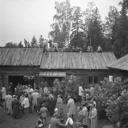 Motiv: (ingen anteckning) ;
En folksamling står kring en midsommarstång, en folksamling vid ett hus, en kyrkbåt ros av kvinnor och män i folkdräkt, en folksamling står vid en brygga med en kyrkbåt.