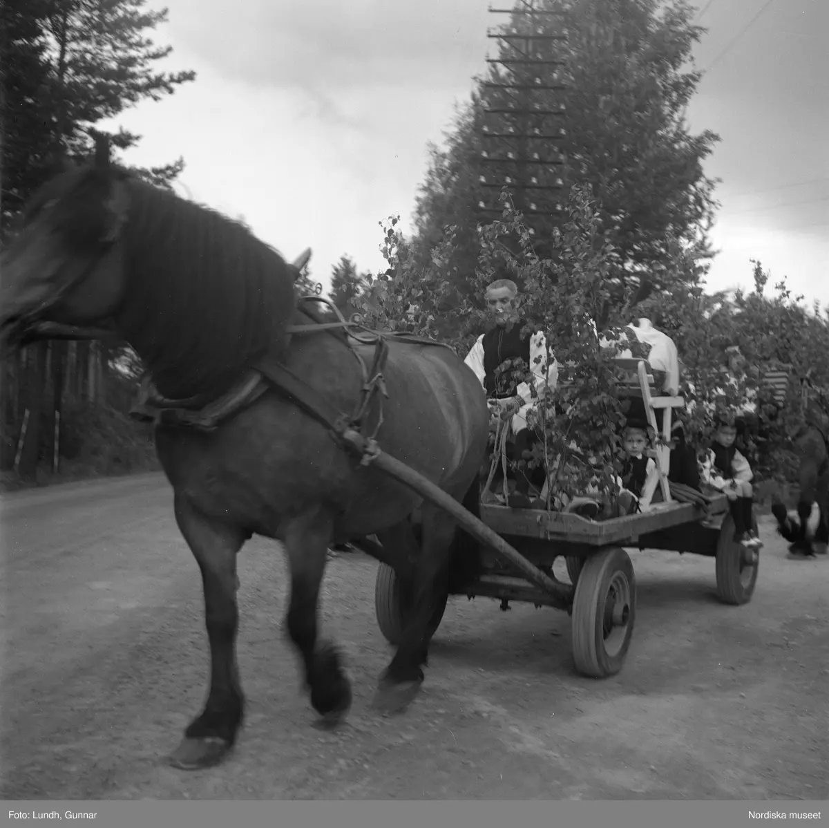 Motiv: midsommarfirande i Rättvik - Leksand ;
En pojke i folkdräkt och en flicka står vid en midsommarstång, en flicka pussar en pojke, en kvinna och en man handlar trasmattor av en man i en försäljningsvagn med text "Hemslöjd", en kvinna står vid en bil med kopparsaker till försäljning och en skylt "Ruben I Redin", en kvinna och en man i folkdräkt håller lövade ringar, kvinnor i folkdräkt går på en väg, en man kör en hästdragen vagn, ett led av kvinnor och män i folkdräkt bär en lövad girlang, människor åker på hästdragna vagnar.