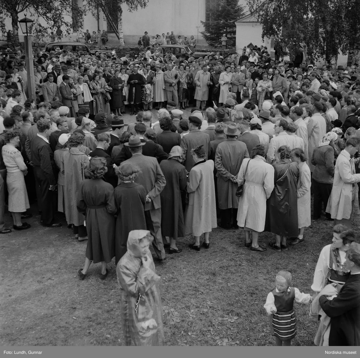 Motiv: (ingen anteckning) ;
En folksamling vid Rättviks kyrka, en folksamling står vid en brygga när kvinnor och män går ombord på två kyrkbåtar.