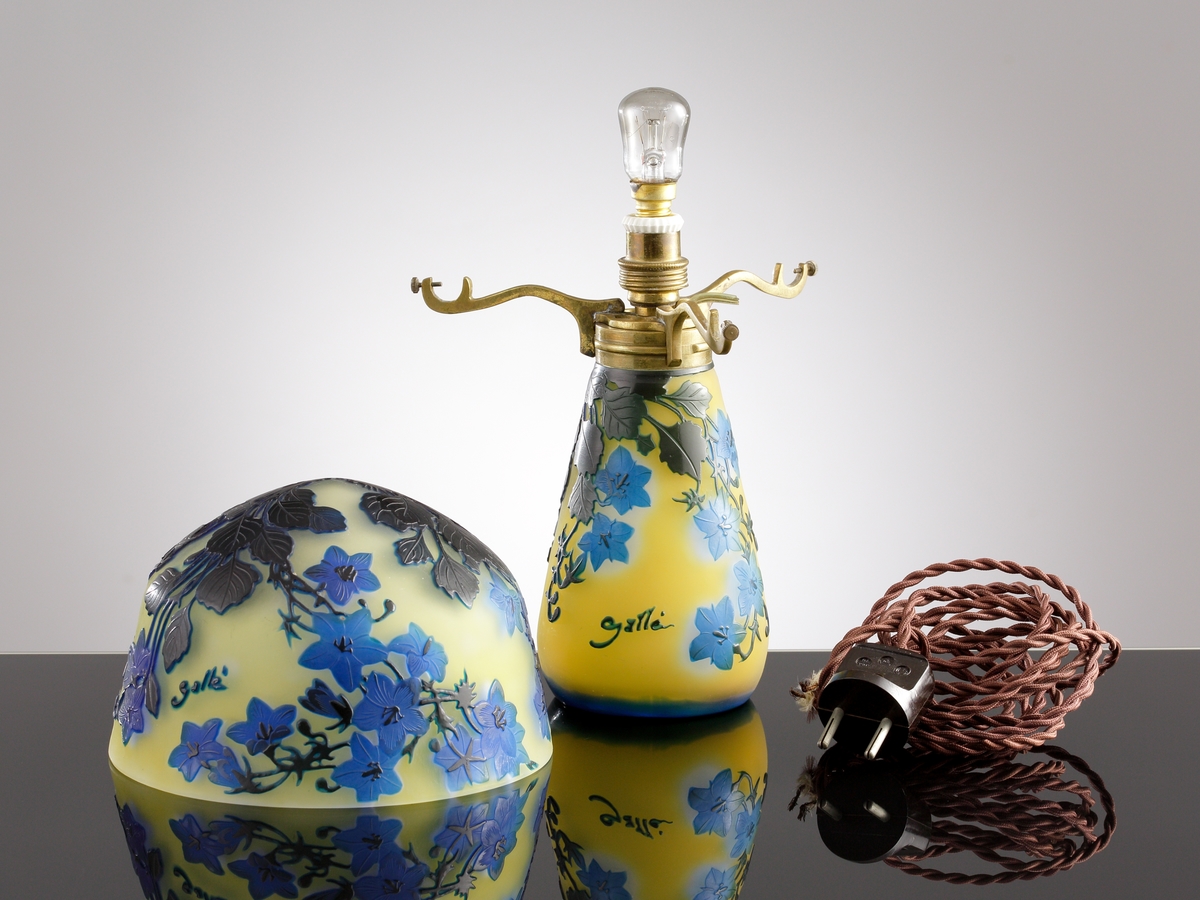 Opak, gul lampa med etsat överfång i olika blå nyanser.
Metallfattning för glödlampa. Tvinnad textilsladd.