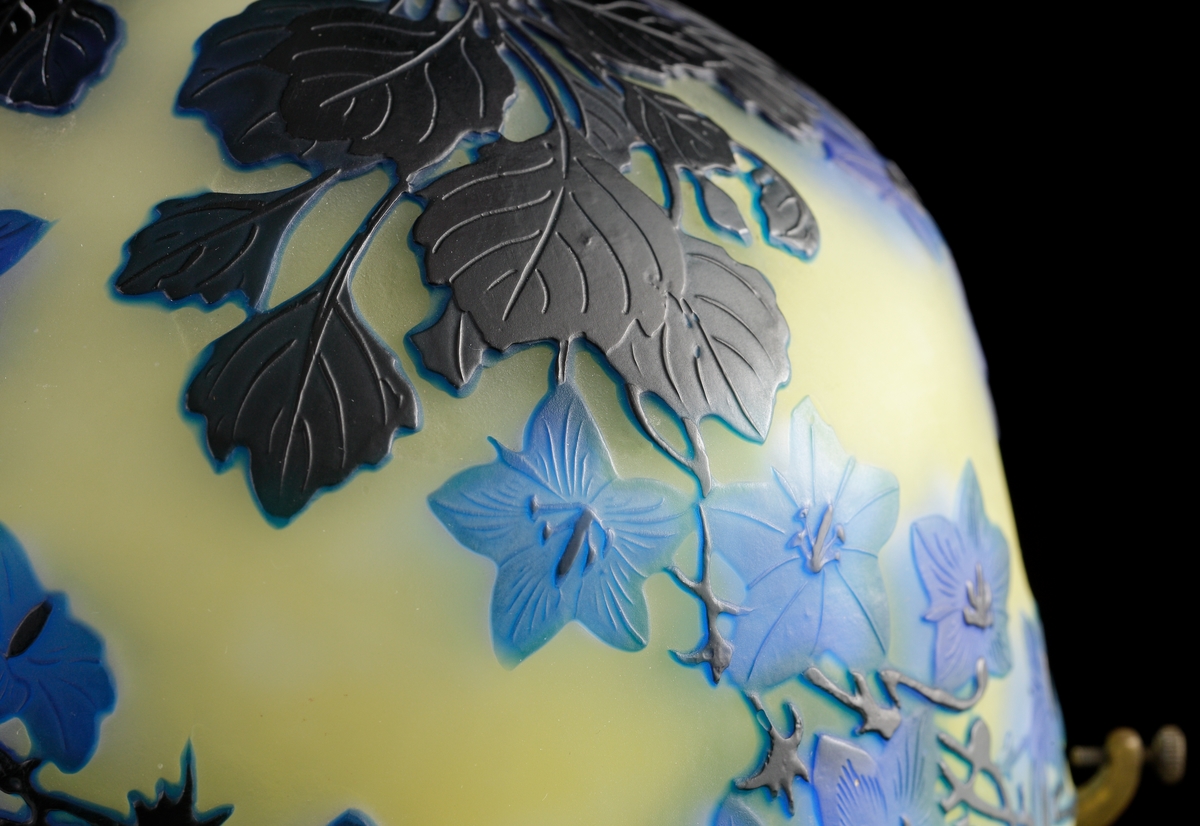 Opak, gul lampa med etsat överfång i olika blå nyanser.
Metallfattning för glödlampa. Tvinnad textilsladd.