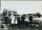 Möklinta sn, Sala.
Män kvinnor och barn framför bostad. Kvinnorna med förkläden. Början av 1900-talet.