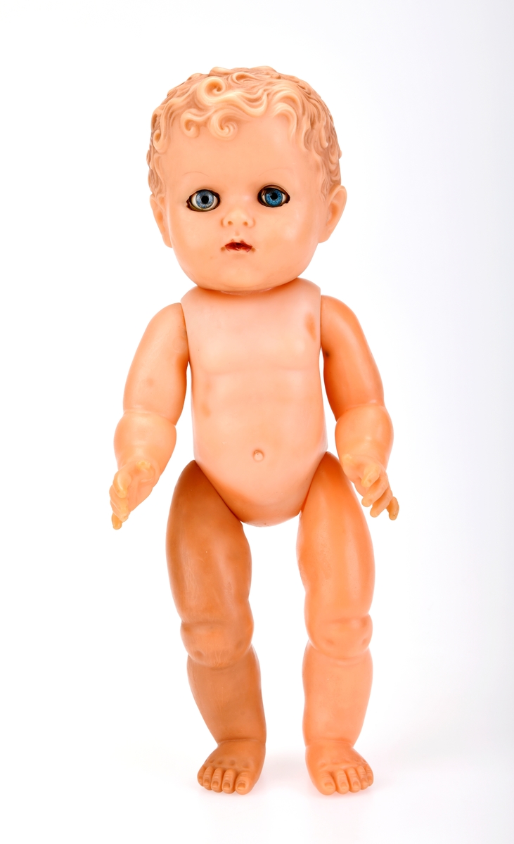 En dukke/babydukke laget av myk plast. Armer og bein er bevegelige i en retning.  Fingre og tær er støpt med detaljer som negler. Dukken har også markert navle. Håret er støpt og er krøllete. Håret er brunt. I ansiktet er munnen malt rød. Det er åpning i munnen til å sette inn en tåteflaske. Dukken har også et "tissehull". Dukken har blå glassøyne som blunker. Øyenvippene er av nylon og er brune. I følge giver ble dukken kalt "Lærdalsdukken", og denne hadde navnet "Krølltopp".