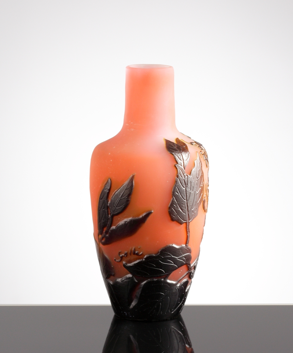 Röd opak vas med blomstermotiv i brunrött etsat överfång.