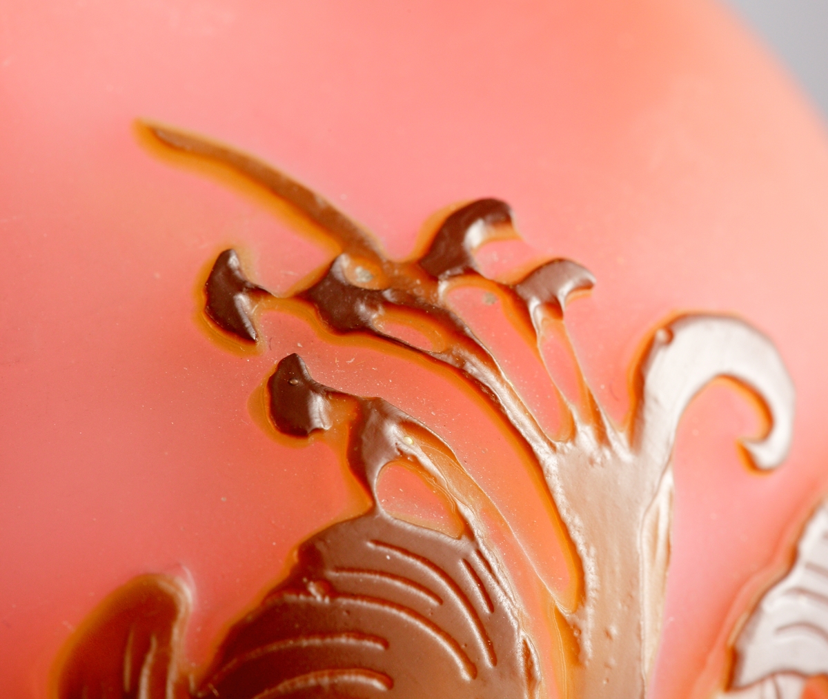 Röd opak vas med blomstermotiv i brunrött etsat överfång.