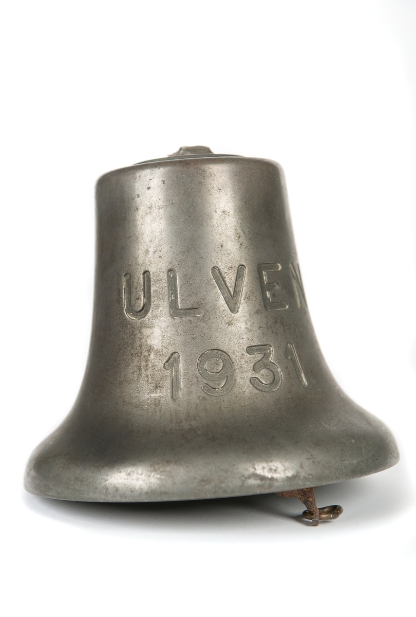 Skeppsklocka av malm med kläpp av järn. Ingraverat "ULVEN 1931". Upphängningsbygeln avslagen. Har tillhört ubåten ULVEN.