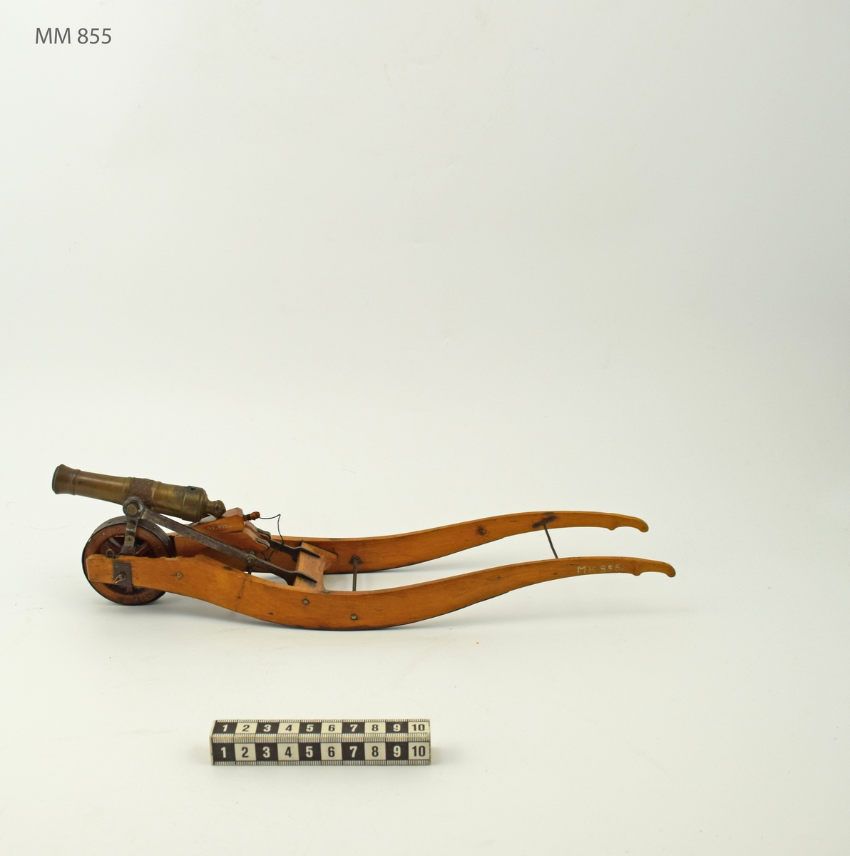 Modell av kanonskottkärra med 2-p metallnicka. Kärran av trä med järnbeslag. Nickan märkt "XII : IV". Tillbehör: 1 st riktkil. Troligen Chapman. Lavetten L = 350 mm B = 85 mm H = 85 mm.