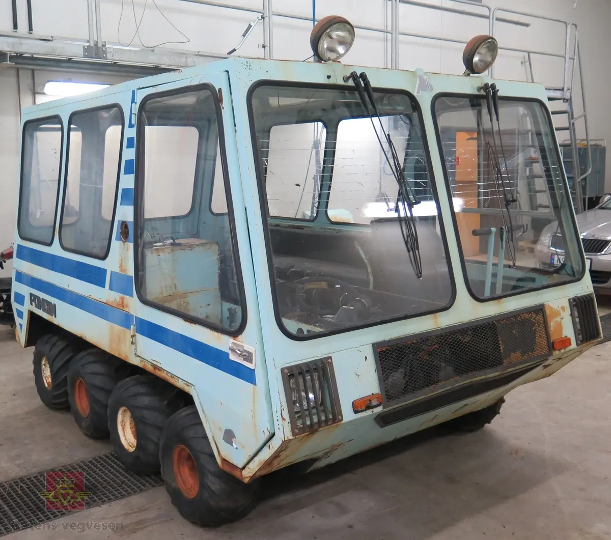 Lyseblå og mørkeblå buss med belter, 8 x 8. 4-sylindret dieselmotor, trolig fra Peugeot eller Renault. Kan brukes både som hjul- og som beltebuss.