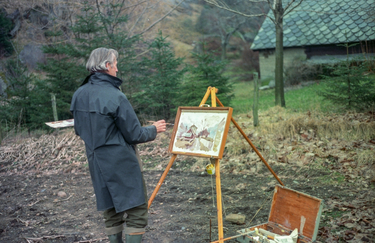 Ragnar Grønsdal målar Hjøllotunet midt på 1980-talet. Eldhus i bakgrunn. 