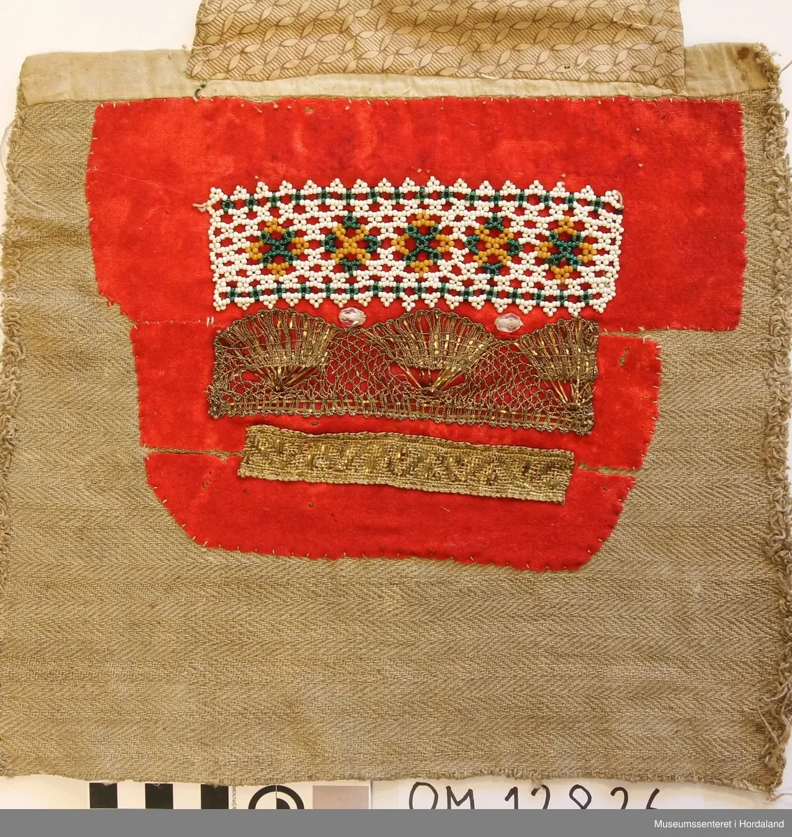 Bringeduk med eit perlenett forma som ei borde oppe og rett nedafor den er det to litt store, blanke glassteinar, så kjem ei brei metalborde i knipling og eit smalare vevd band i metall. Alt dette er montert på raudt bomullsflanell. Bakstykket er eit stykke grovt heimevove linstoff. Opp er bakstykket kanta med eit smalt stykke bomullslerret. Utanpå/ovanfor der att er det påsydd eit brunmønstra bomullstoff.