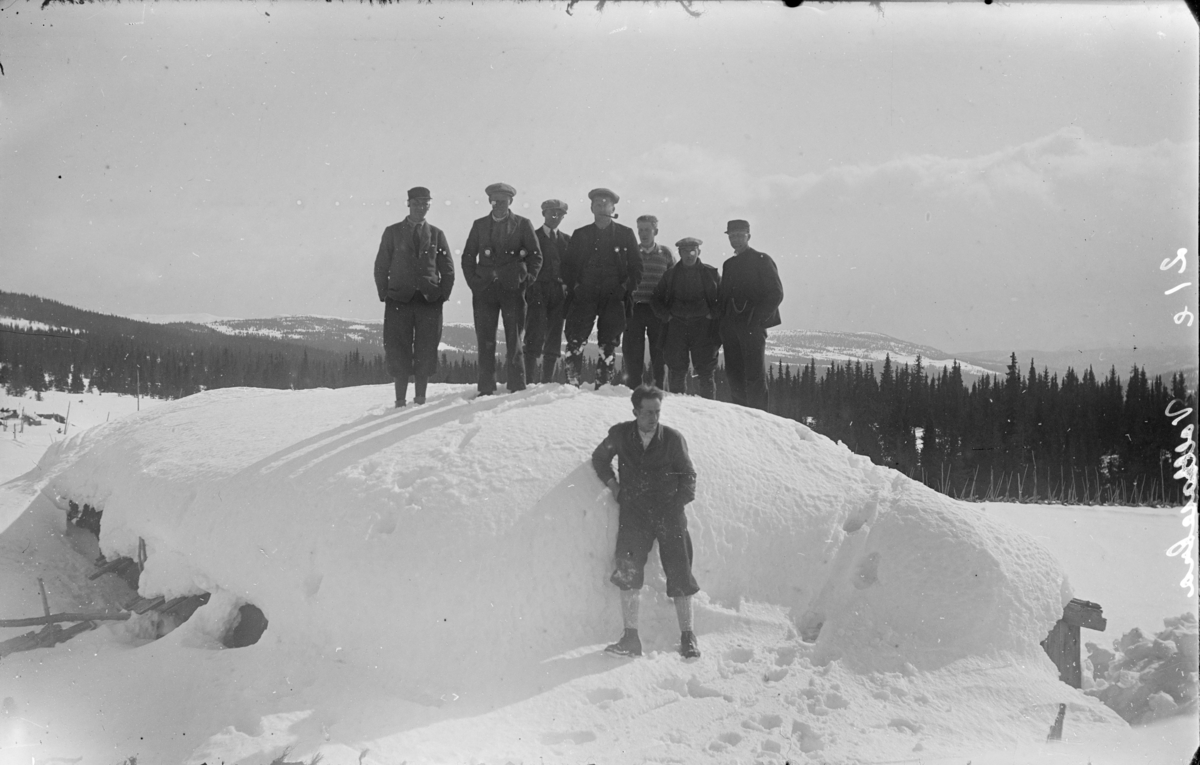 8 menn ved en nedsnødd hytte i Gausdal Vestfjell, påsken 1931. Foran er fotografen Karl Olav Moe.