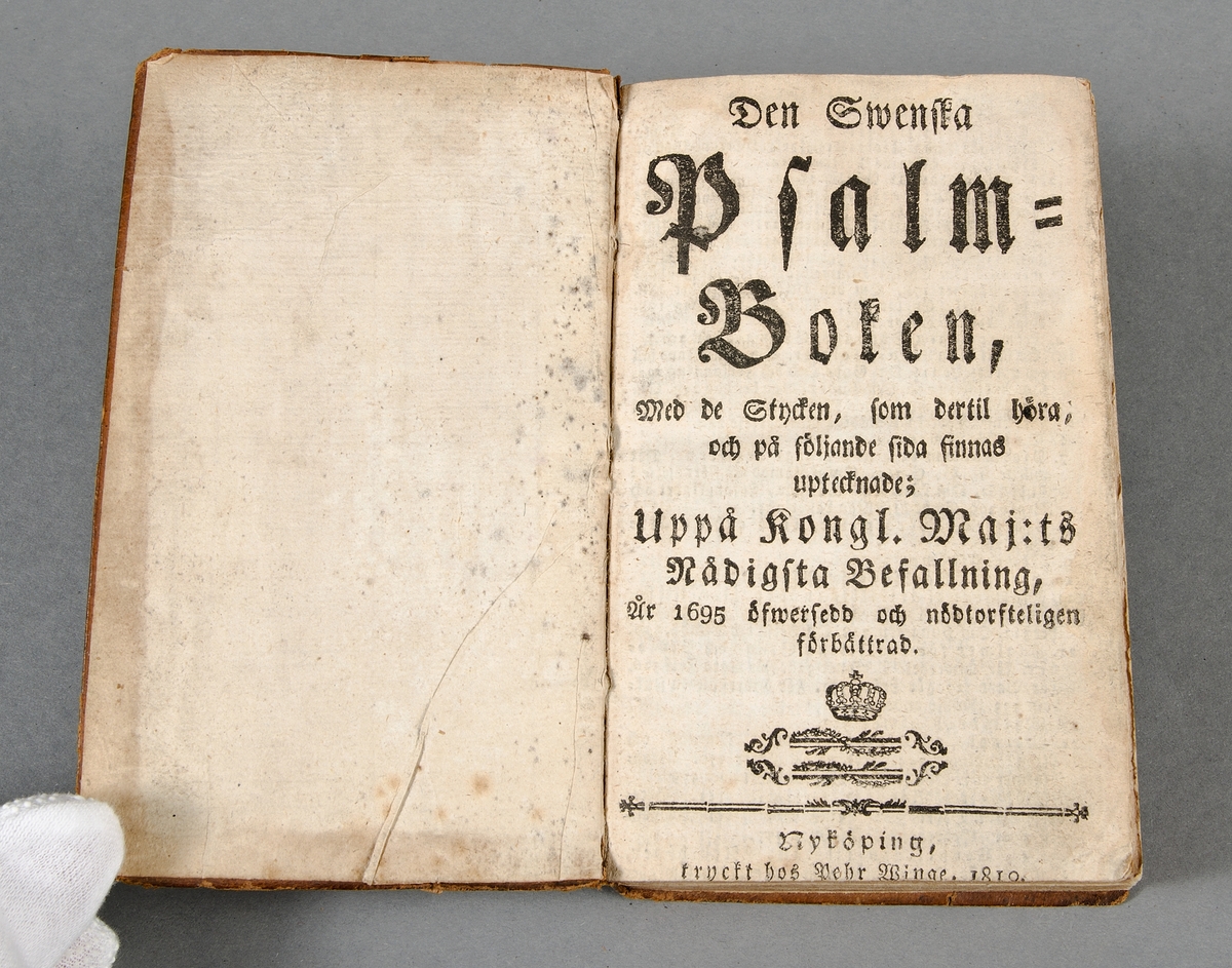 Psalmbok. Skinnpärmar med pressat mönster bl.a. i form av hjärtan med texten "Med Gud och Dig Trolofwar Jag Mig". Tryckt i Nyköping 1810. Bläckinskrift på pärmens bakre insida: "Brita Mats Do..." är föd 1788 i fund-Bo socken Byre By och in... i acktenskap år 181? den 28 December med Rettaren Johan Eric Kihlgren på Håga Gård och Haga socken.