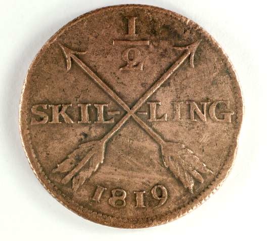 Präglat mynt, av koppar. 1/2 skilling. Åtsida; tre kronor, myntherrens krönta initialer:
C XIV samt omskrift: FOLKETS KÄRLEK MIN BELÖNING. Frånsida: två korslagda pilar samt texten: 1/2 SKILLING 1819. 
Mindre skador.