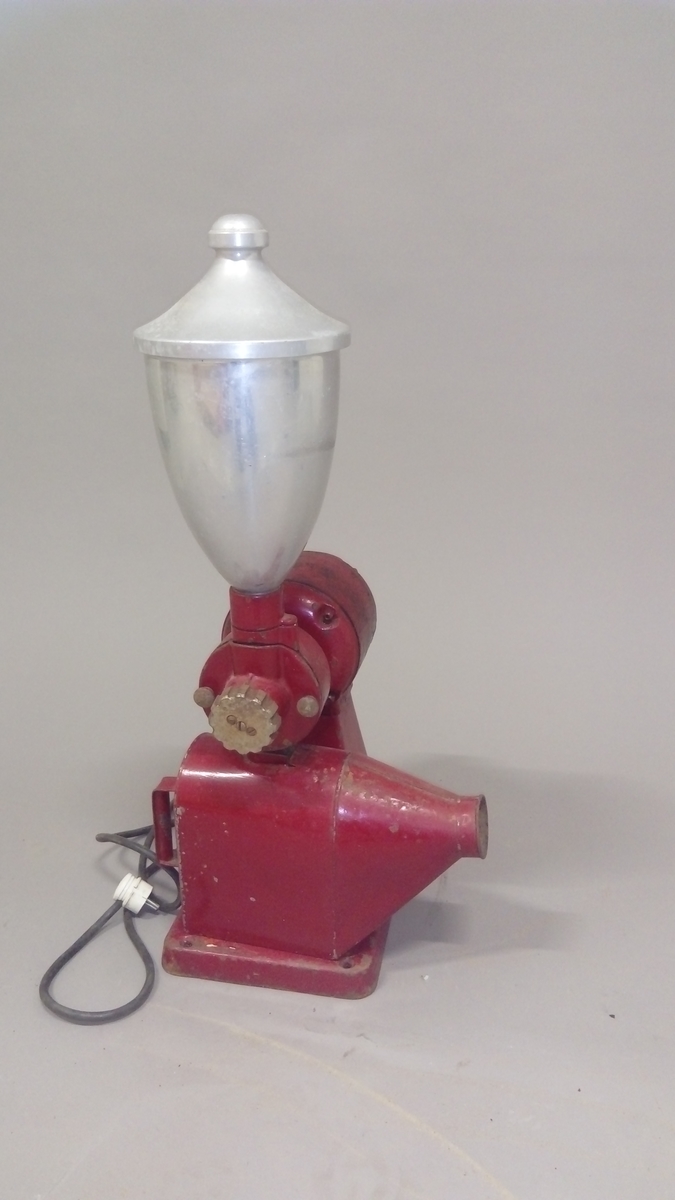 Elektrisk kaffekvern brukt i butikk. 
Kaffebønner helles i maskinen og males til kaffe, fortrinnsvis for kokkaffe.
Er komplett med avtagbar beholder for å fylle den ferdig malte kaffen i poser evt annet, samt ledning med støpsel. 

Maskina er rødlakkert, er slitt med noe rust og rester av olje eller fett.