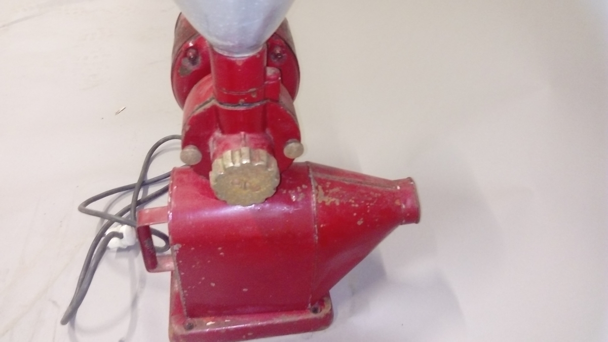 Elektrisk kaffekvern brukt i butikk. 
Kaffebønner helles i maskinen og males til kaffe, fortrinnsvis for kokkaffe.
Er komplett med avtagbar beholder for å fylle den ferdig malte kaffen i poser evt annet, samt ledning med støpsel. 

Maskina er rødlakkert, er slitt med noe rust og rester av olje eller fett.