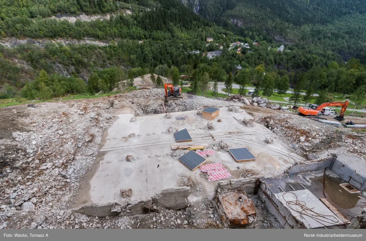Bygningen var opprinnelig Vemork Hydrogenfabrikk som var plassert fem meter foran Vemork gamle kraftstasjon. Bygget var i betong i 8 etasjer. Driften i bygget stoppet i 1971 og ble i 1977 revet ved sprengning. Telemark Fylkeskommune initierte en utgravning på tomten for om mulig å finne rester etter den gamle kjelleren i 2017. 18.09.2017 startet arbeidet og kjelleren ble i november funnet inntakt.