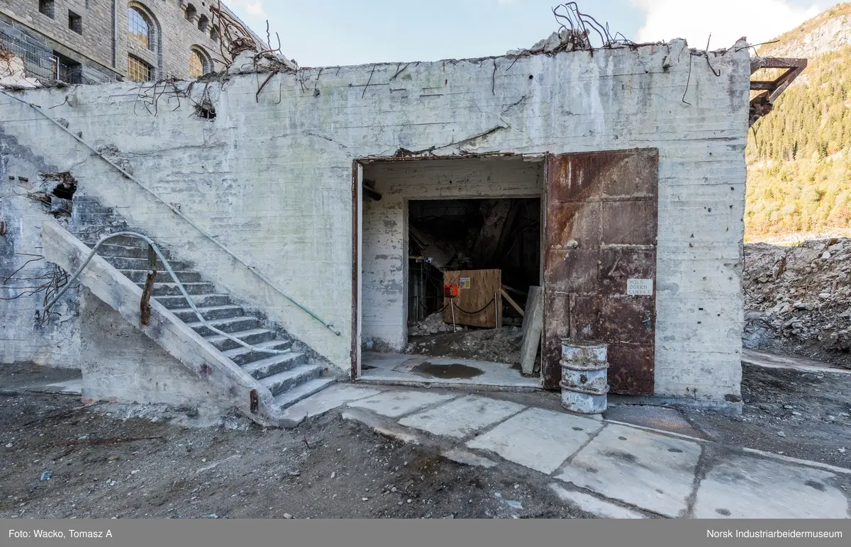Bygningen var opprinnelig Vemork Hydrogenfabrikk som var plassert fem meter foran Vemork gamle kraftstasjon. Bygget var i betong i 8 etasjer. Driften i bygget stoppet i 1971 og ble i 1977 revet ved sprengning. Telemark Fylkeskommune initierte en utgravning på tomten for om mulig å finne rester etter den gamle kjelleren i 2017. 18.09.2017 startet arbeidet og kjelleren ble i november funnet inntakt.