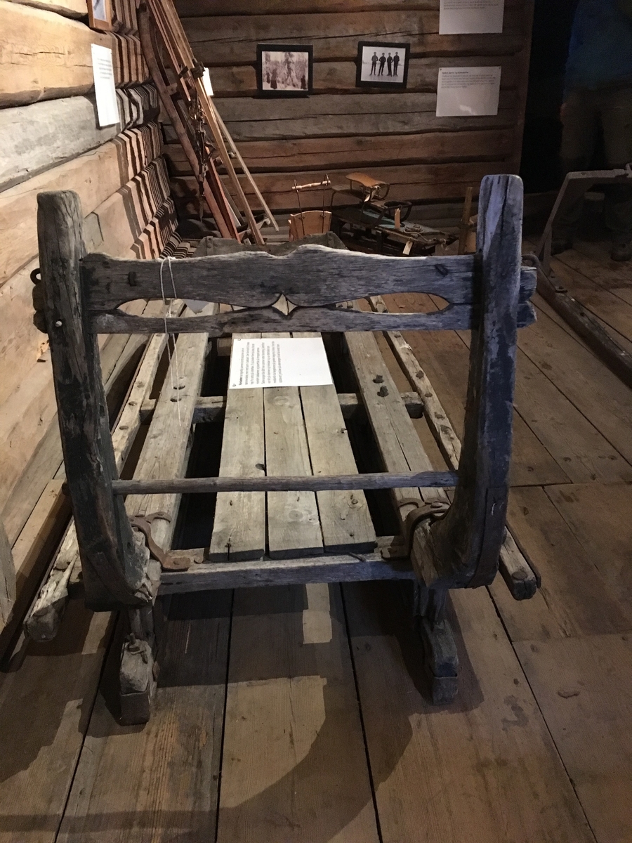 Høyslede (transport av vinterfôr) med høy bakkarm og lav framkarm. Dragfeste for slededrag. Hengsler til forkarm. Treplugger på begge sider av bukkene ned i meier. Krok til grinder på bakkarm. Tverrbrett med gjennomskåret dekor. Transportredskap til hest hovedsakelig brukt av menn.

Tilstand: slitt