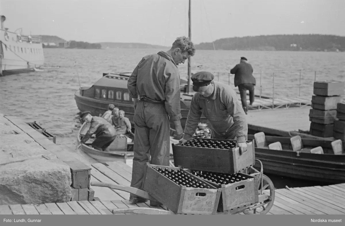 Motiv: Stockholm - Vaxholm;
Människor på en brygga med skylt "Edlunda", en segelbåt, människor på en brygga med skylt "Höganäs".

Motiv: Vaxholm;
Människor står på en brygga och en båt lägger till, en segelbåt, två män lyfter backar med flaskor på en brygga, folksamling vid möbler utställda på en grusplan (troligen en auktion).