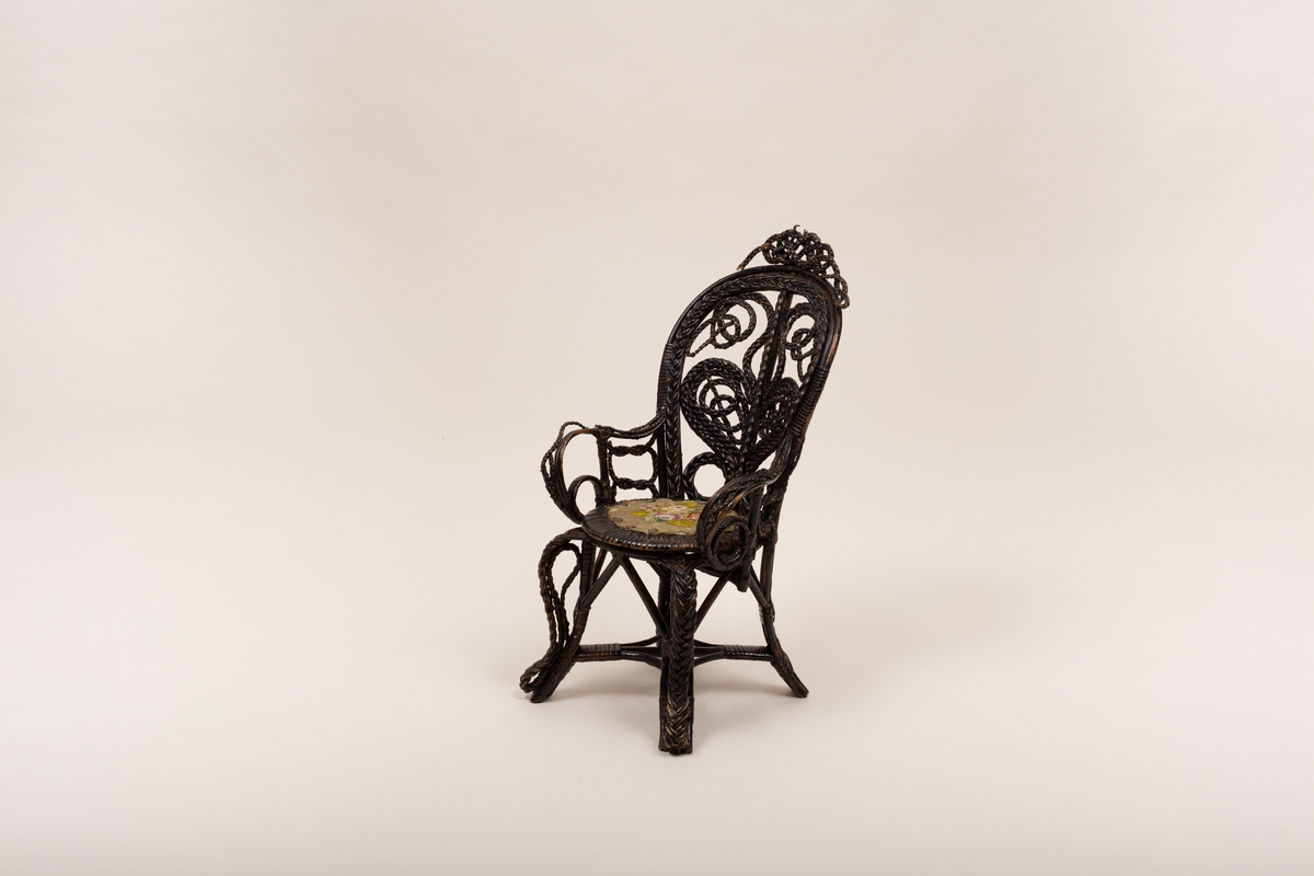 Dukkemøbel, stol i flettverk, sortmalt. Rund, brodert tekstilpute, blomstermotiv.