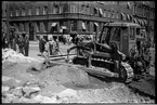 Arbete med en schaktmaskin på Vasagatan för färdigställande av en viadukt mellan Stadshusbron och Tegelbacken i Stockholm.