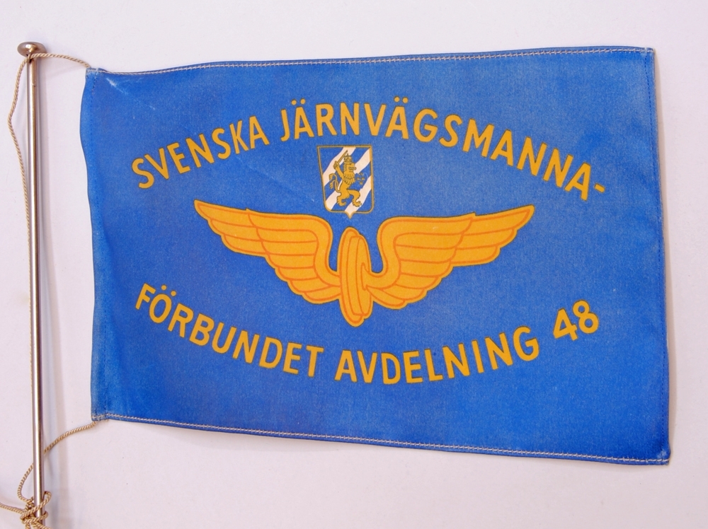 Bordsstandar med en ljusblå rektangulär flagga. På flaggan finns texten: "SVENSKA JÄRNVÄGSMANNAFÖRBUNDET AVDELNING 48", tryckt i guld. På mitten av flaggan finns Göteborgs stadsvapen tryckt. Stadsvapnet föreställer ett lejon bärande krona, lejonet håller i ett svärd och en sköld med tre kronor på. Färgsättningen på stadsvapnet är vit, blå och guld. Under vapnet finns det bevingade hjulet i guld. 

Bordsstandarens stång är metallfärgad och har en cirkelformad fot. Flaggan är fäst i stången med ett grått snöre.